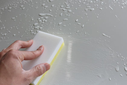 メンテナンスクリーナーを専用スポンジで施工する様子